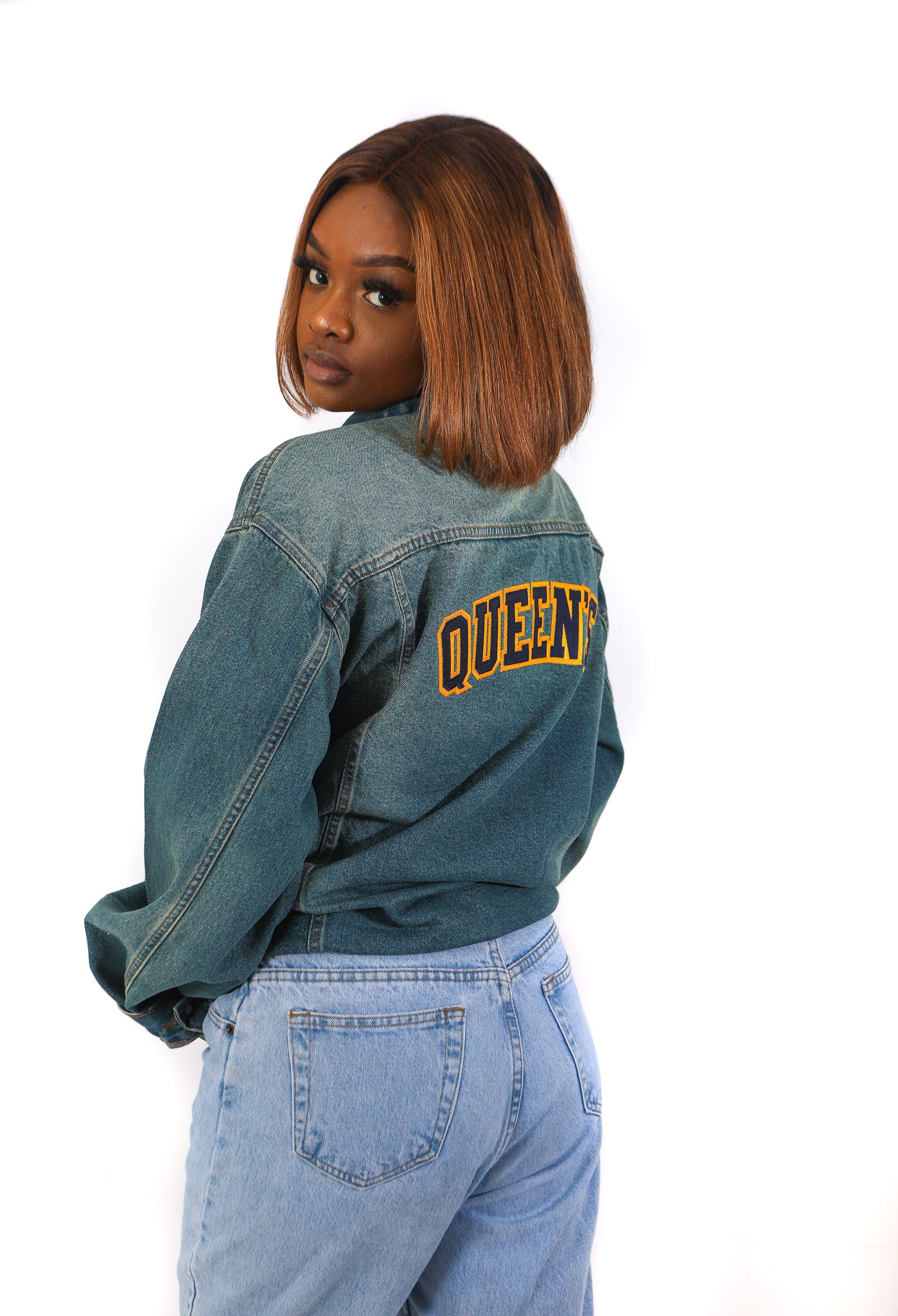 Back of our oversized vintage jean jacket with embroidered "QUEEN'S" in navy and gold across the back